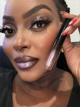 Close-up of a woman with sparkly makeup holding a lip gloss.