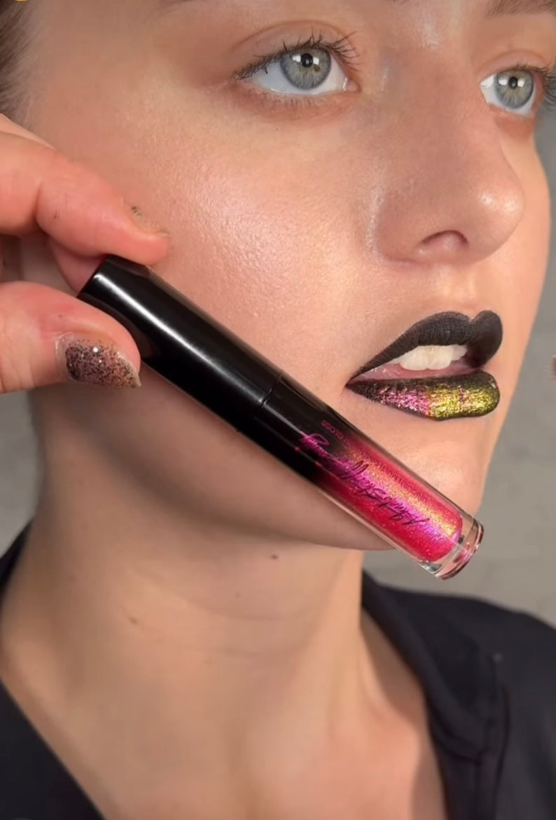 A woman with black and multi-color lips holding a lip gloss tube.
