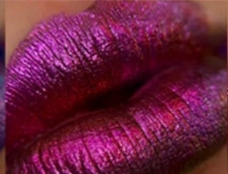 Here are some descriptive alt tags for the image, focusing on the visible details:

*   Closeup of full lips with metallic purple and red lipstick.
*   Lips with shimmery, iridescent purple lipstick.
*   Macro shot of lips painted with shiny, textured purple lipstick.